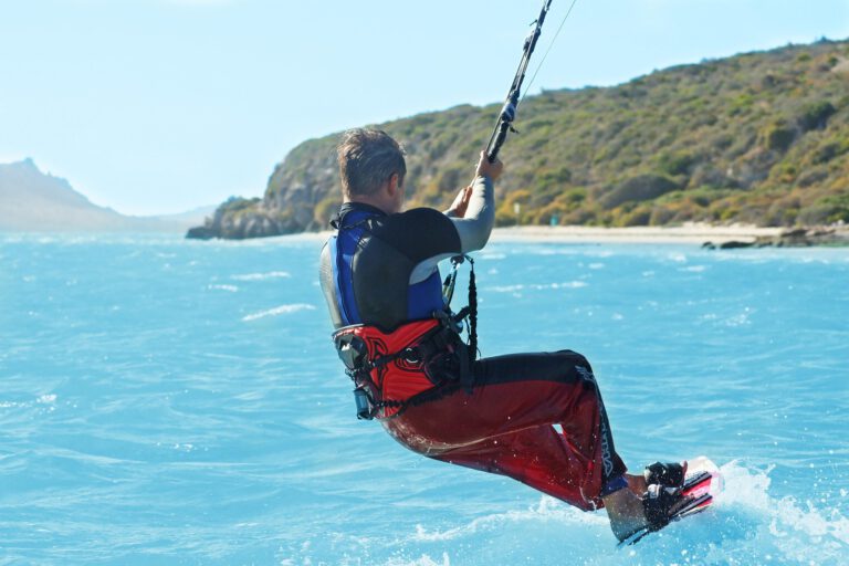 Kitesurfer in rotem Neoprenanzug auf türkisblauem Meer in der Karibik
